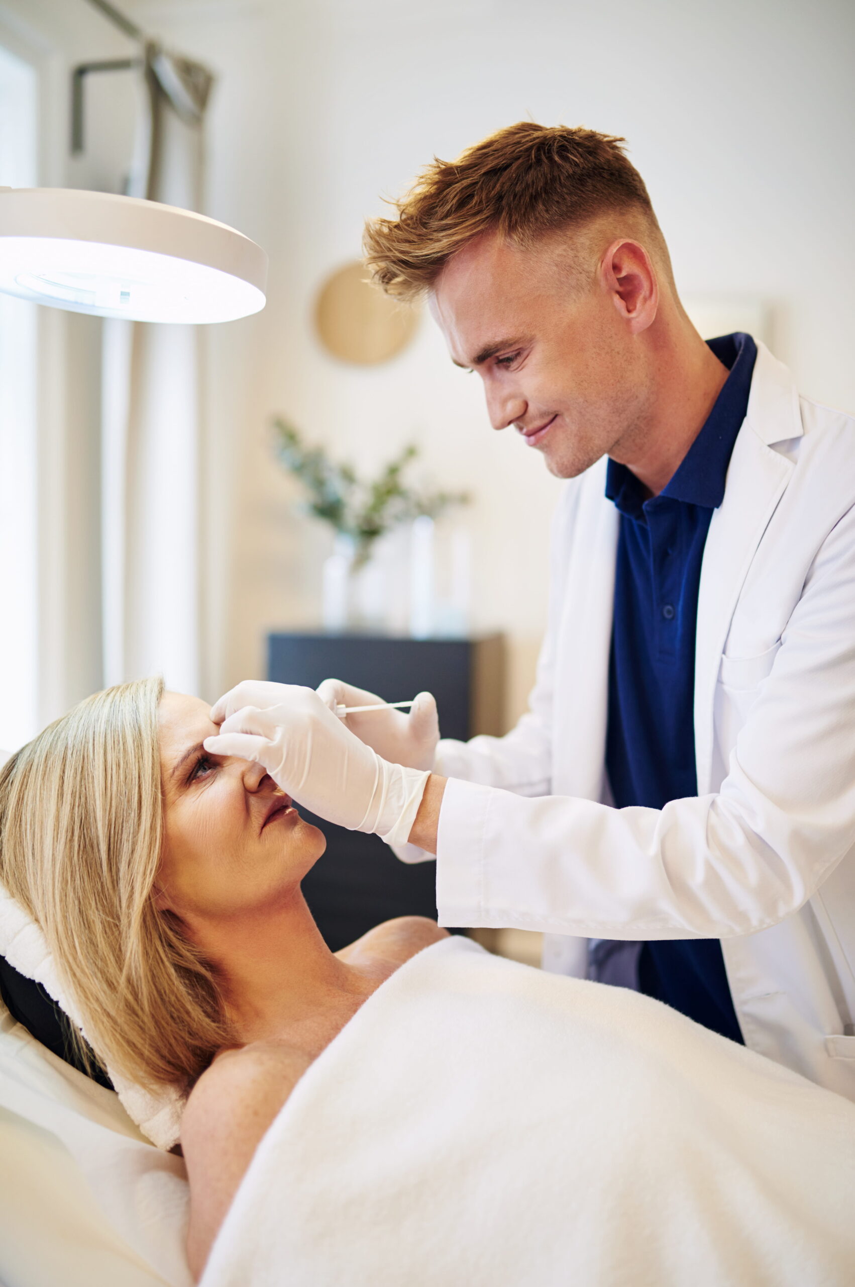 Doctor injecting botox into the forehead of a mature woman