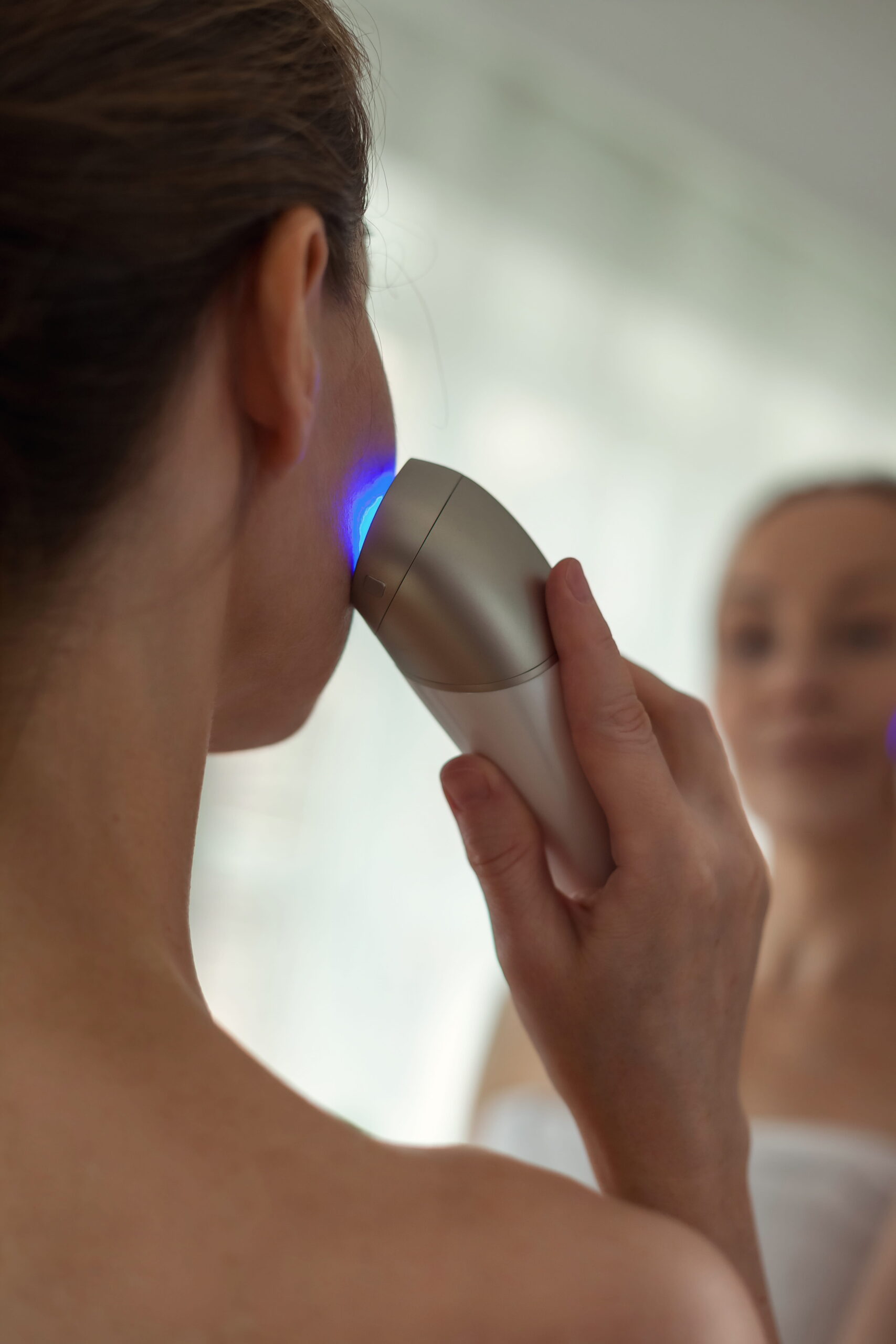 Woman Using Beauty Device Looking in Mirror